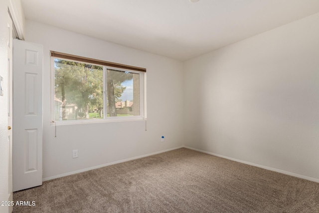 carpeted empty room featuring baseboards