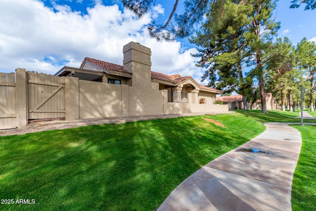 back of property with a tile roof, a gate, fence, a yard, and stucco siding