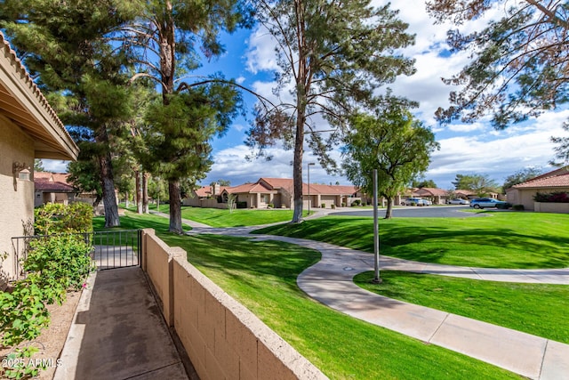 surrounding community with a residential view, fence, and a lawn