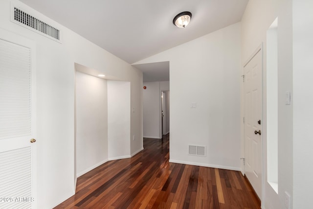 corridor featuring lofted ceiling, dark wood finished floors, visible vents, and baseboards