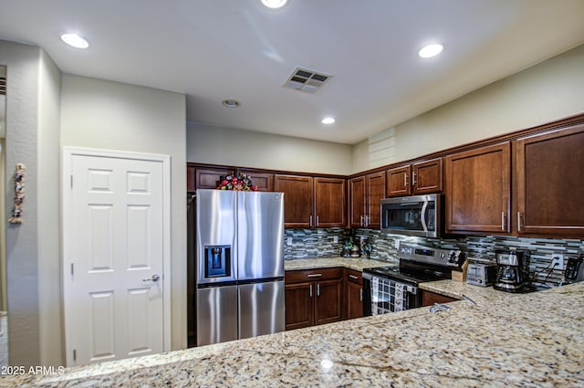 kitchen featuring light stone counters, backsplash, and stainless steel appliances