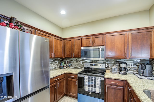 kitchen with light stone counters, backsplash, light tile patterned flooring, and appliances with stainless steel finishes