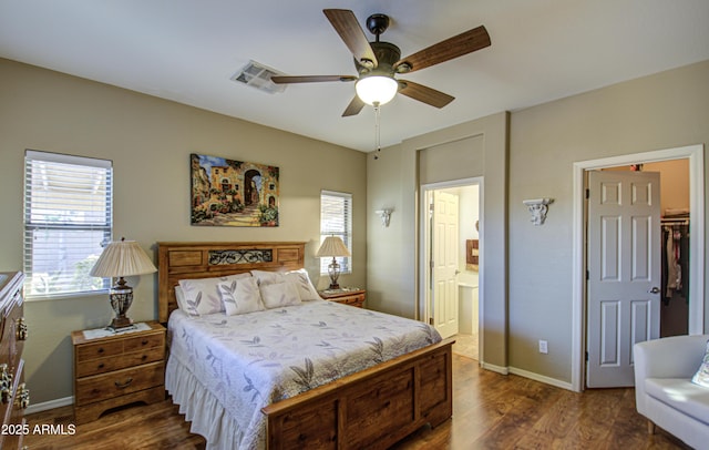 bedroom with dark wood-type flooring, ceiling fan, connected bathroom, and a spacious closet