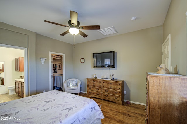 bedroom with ceiling fan, a walk in closet, dark hardwood / wood-style flooring, and ensuite bath