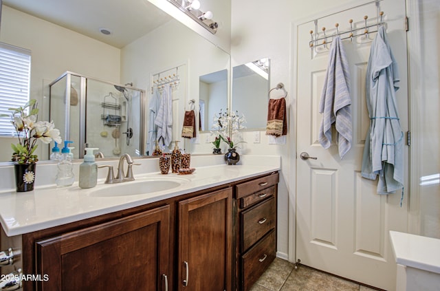 bathroom with a shower with door, vanity, and tile patterned floors