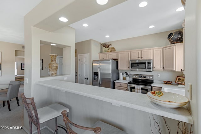 kitchen with a breakfast bar, a peninsula, light countertops, and stainless steel appliances