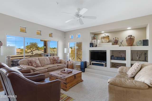 carpeted living area featuring built in shelves and a ceiling fan