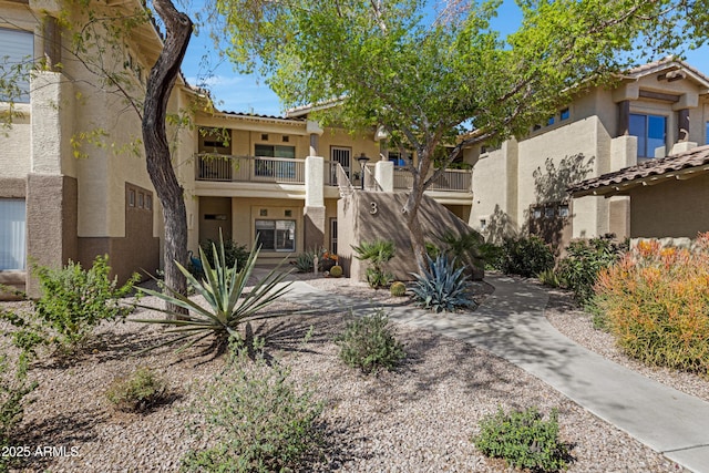 view of front of house featuring stucco siding, a balcony, and a tiled roof