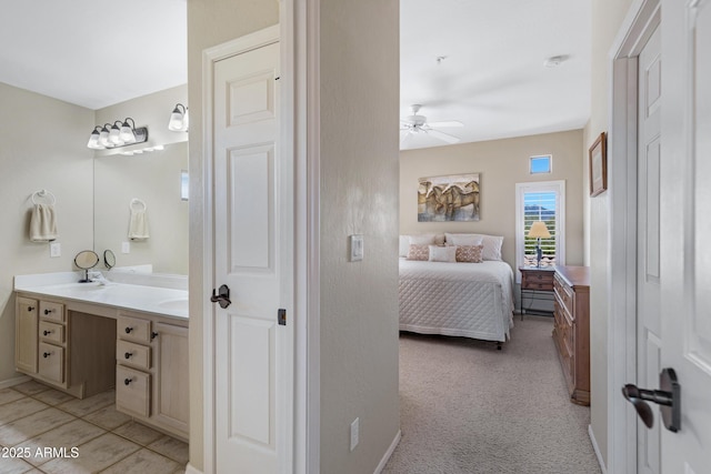 full bathroom with ensuite bath, double vanity, a ceiling fan, and baseboards