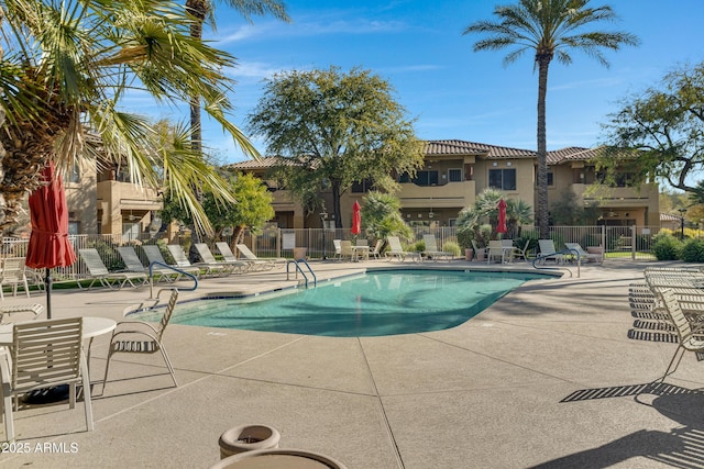 pool with a patio area and fence