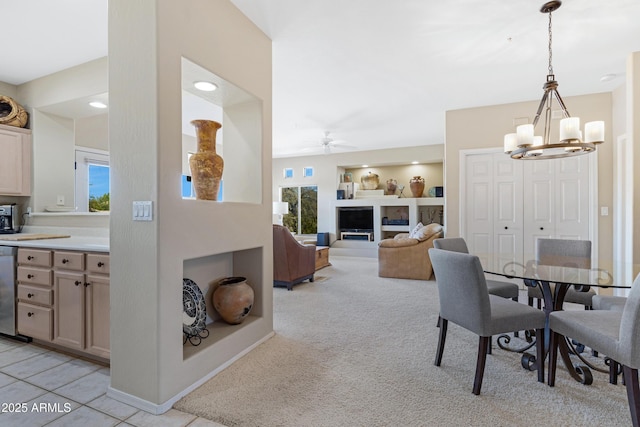 dining room with light carpet, ceiling fan with notable chandelier, built in shelves, and baseboards