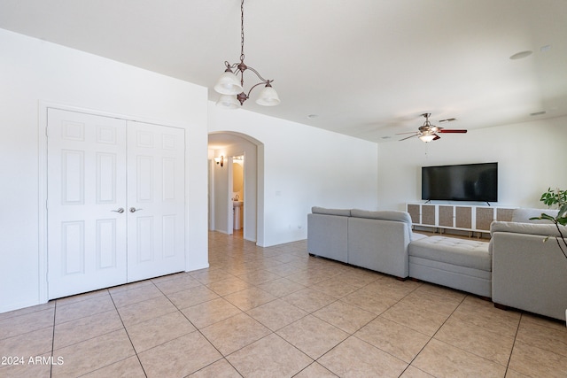 unfurnished living room with ceiling fan with notable chandelier and light tile patterned floors