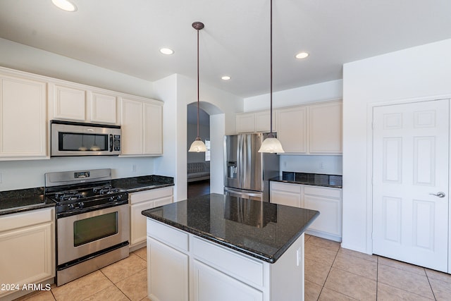 kitchen with appliances with stainless steel finishes, hanging light fixtures, a kitchen island, and light tile patterned floors