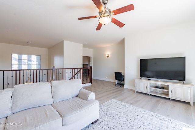 living room with ceiling fan with notable chandelier and light wood-type flooring