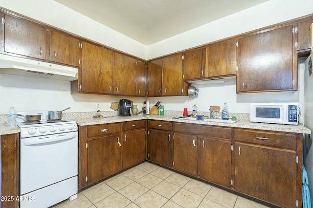 kitchen featuring white appliances, light tile patterned floors, under cabinet range hood, and light countertops