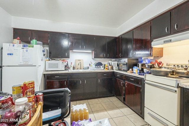 kitchen featuring light tile patterned floors, light countertops, a sink, white appliances, and under cabinet range hood