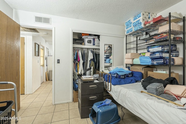 bedroom with a textured ceiling, visible vents, a closet, and light tile patterned flooring