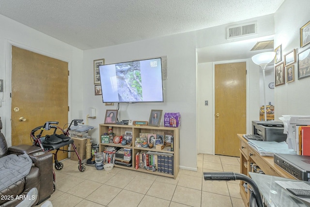 living area featuring a textured ceiling, light tile patterned flooring, and visible vents