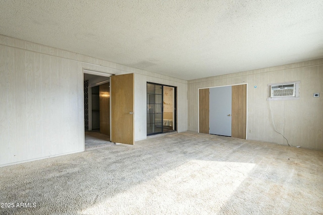 unfurnished room featuring a textured ceiling, carpet, and a wall unit AC