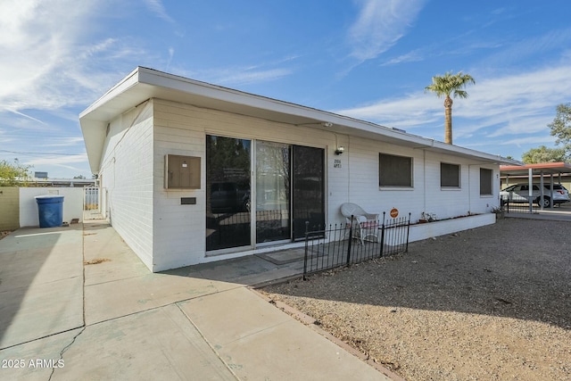 view of front of home featuring driveway, a carport, and fence