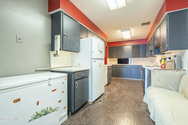 kitchen with visible vents, dark wood-style floors, freestanding refrigerator, light countertops, and white fridge