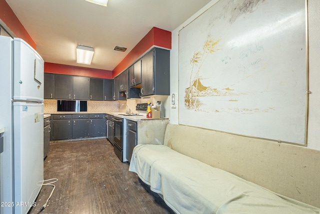 kitchen featuring dark wood-style floors, visible vents, freestanding refrigerator, electric range oven, and tasteful backsplash