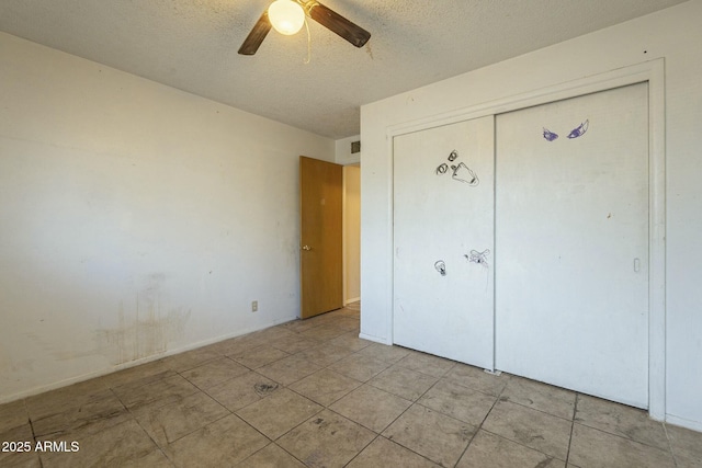 unfurnished bedroom with a closet, light tile patterned flooring, ceiling fan, and a textured ceiling