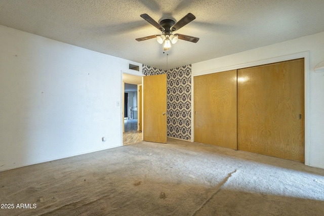 carpeted empty room featuring a ceiling fan, visible vents, and a textured ceiling