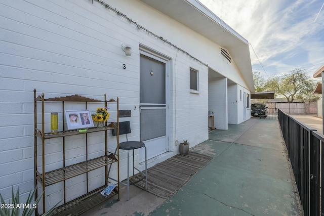 exterior space with concrete block siding, a patio area, and fence