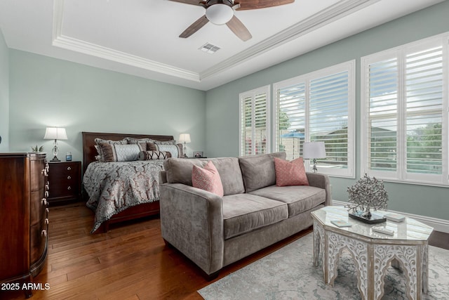 bedroom with visible vents, multiple windows, a tray ceiling, and dark wood-style floors