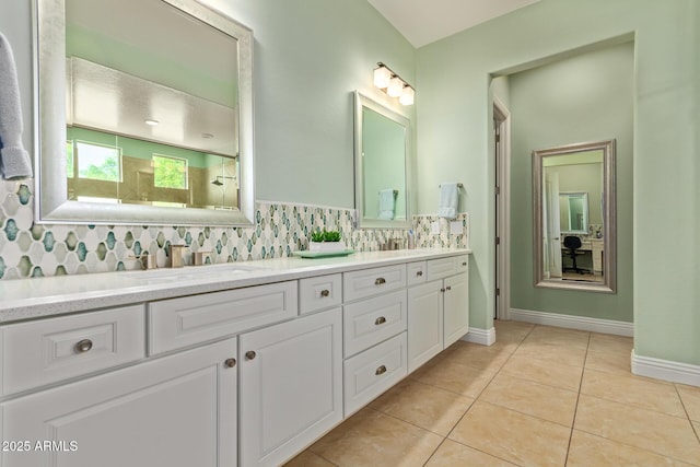 full bath featuring baseboards, a sink, double vanity, backsplash, and tile patterned flooring