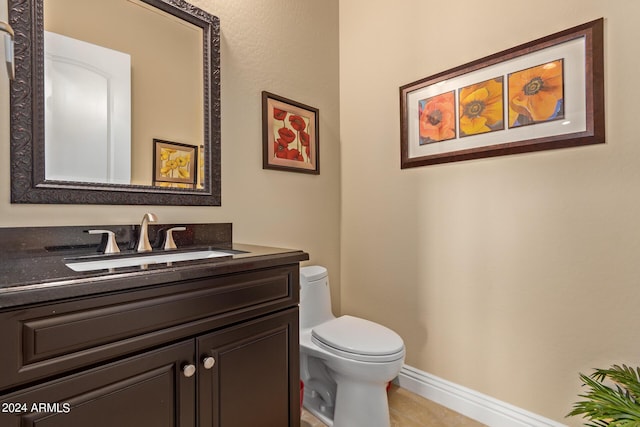 half bathroom with tile patterned flooring, vanity, baseboards, and toilet