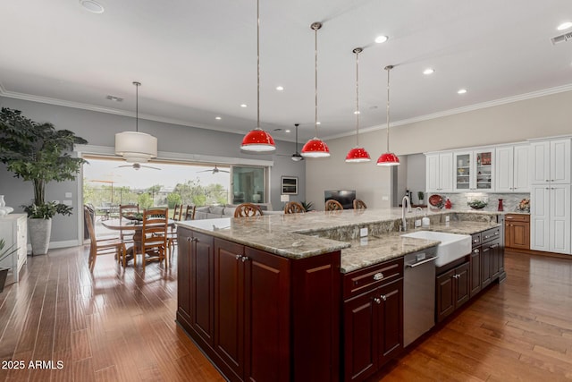 kitchen with glass insert cabinets, a sink, crown molding, wood finished floors, and stainless steel dishwasher
