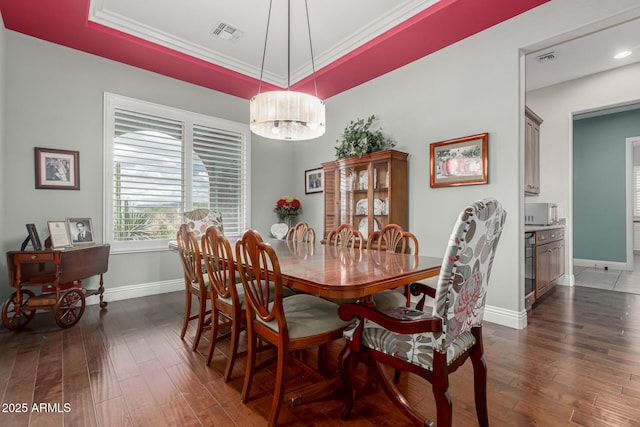 dining room featuring a tray ceiling, baseboards, dark wood finished floors, and visible vents