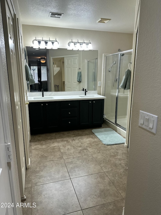 bathroom featuring vanity, a shower with shower door, and a textured ceiling