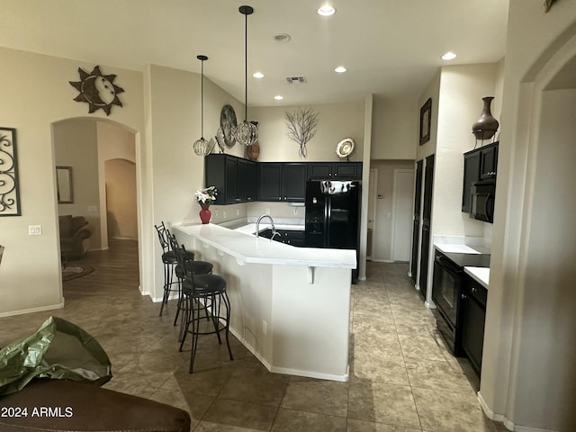 kitchen with sink, a kitchen breakfast bar, kitchen peninsula, pendant lighting, and black appliances