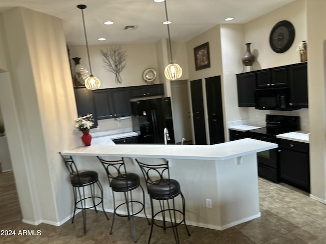 kitchen featuring kitchen peninsula, a breakfast bar, sink, black appliances, and pendant lighting