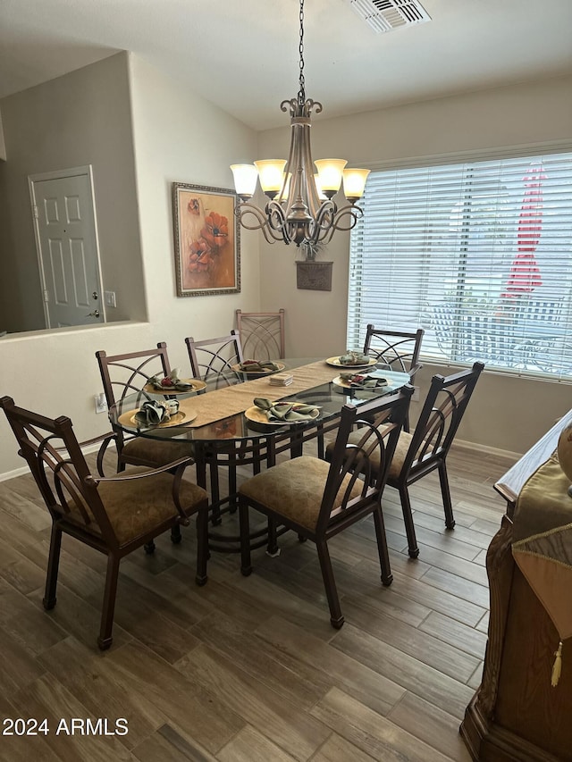 dining space featuring hardwood / wood-style flooring and an inviting chandelier