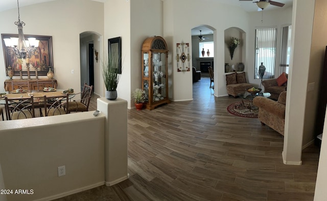 living room featuring dark hardwood / wood-style floors, ceiling fan with notable chandelier, and vaulted ceiling