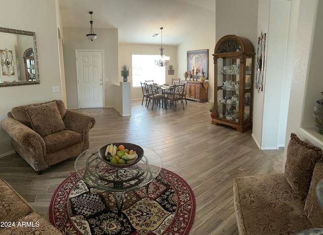 living room with lofted ceiling, wood-type flooring, and an inviting chandelier