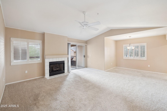 unfurnished living room featuring baseboards, lofted ceiling, a tile fireplace, ceiling fan with notable chandelier, and light colored carpet