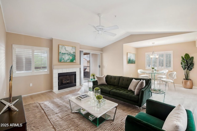 living room with a healthy amount of sunlight, a tile fireplace, ceiling fan with notable chandelier, and lofted ceiling