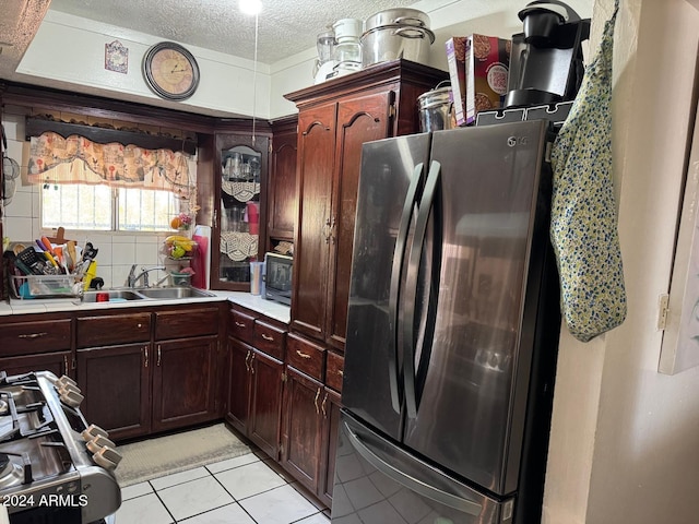 kitchen with appliances with stainless steel finishes, a textured ceiling, light tile patterned flooring, and sink