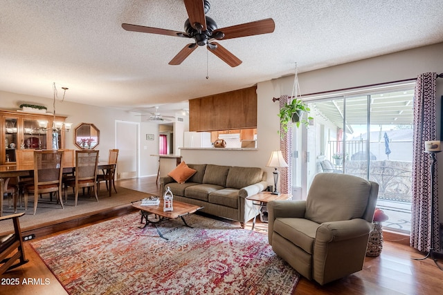 living room featuring hardwood / wood-style flooring, ceiling fan with notable chandelier, and a textured ceiling