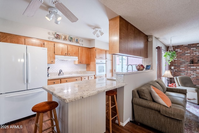 kitchen with white refrigerator, dark wood-type flooring, a textured ceiling, and a kitchen breakfast bar