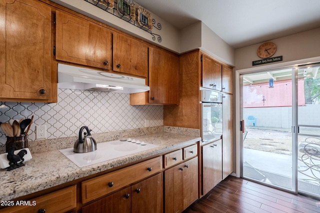 kitchen featuring tasteful backsplash, white stovetop, light stone counters, and wall oven