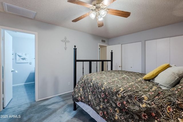 carpeted bedroom featuring multiple closets, a textured ceiling, and ceiling fan