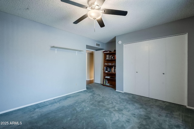 unfurnished bedroom featuring dark carpet, a textured ceiling, ceiling fan, and a closet