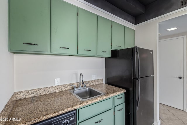 kitchen featuring green cabinets, freestanding refrigerator, a sink, and light tile patterned floors