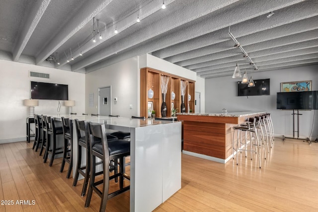 indoor wet bar featuring rail lighting, light wood-style floors, and baseboards